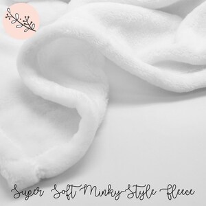 May include: Close-up of a white, soft, minky-style fleece fabric. The fabric is very soft and plush, and it would be perfect for a blanket or a baby's toy.