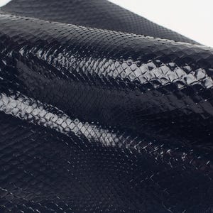 Może przedstawiać: Zbliżenie na ciemnoniebieską skórę węża o błyszczącym wykończeniu. Skóra ma fakturowany wzór przypominający łuski.