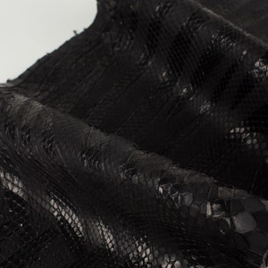 Peut inclure: Cuir de serpent noir avec un motif texturé. Le cuir est doux et souple, avec un éclat naturel.