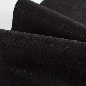 Può includere: Primo piano di pelle sintetica nera con una trama testurizzata a pelle di serpente.