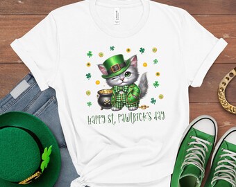 May include: White t-shirt with a cartoon cat in green St. Patrick's Day clothing, including a hat and jacket. The cat winks beside a pot of gold and shamrocks. Text reads "Happy St. Pawtrick's Day".