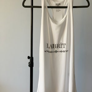 May include: White tank top with a black graphic that says "TEAM" and "LABRÎT" with a star and geometric designs.