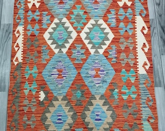 May include: A traditional Turkish rug with a geometric pattern in shades of red, blue, white, and gray. The rug has a fringe border.