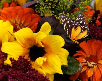 May include: A close-up of a bouquet of yellow, orange, and burgundy flowers with a black and orange butterfly perched on a yellow flower.