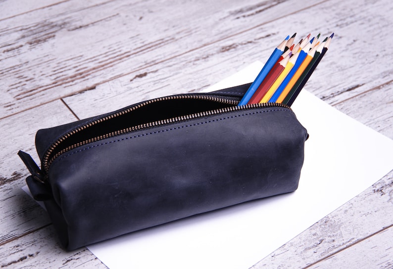Peut inclure: Une trousse &agrave; crayons en cuir bleu fonc&eacute; avec une fermeture &agrave; glissi&egrave;re. La trousse est remplie de crayons de couleur.