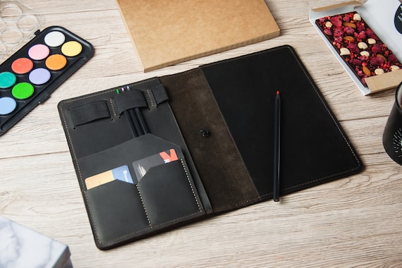 A structured, hand-stitched leather planner cover with monogramming — the kind of desk accessory that feels like an heirloom, not a Amazon order.