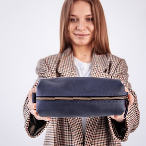 Peut inclure: Une trousse de toilette zipp&eacute;e bleu fonc&eacute; avec une fermeture &eacute;clair dor&eacute;e.
