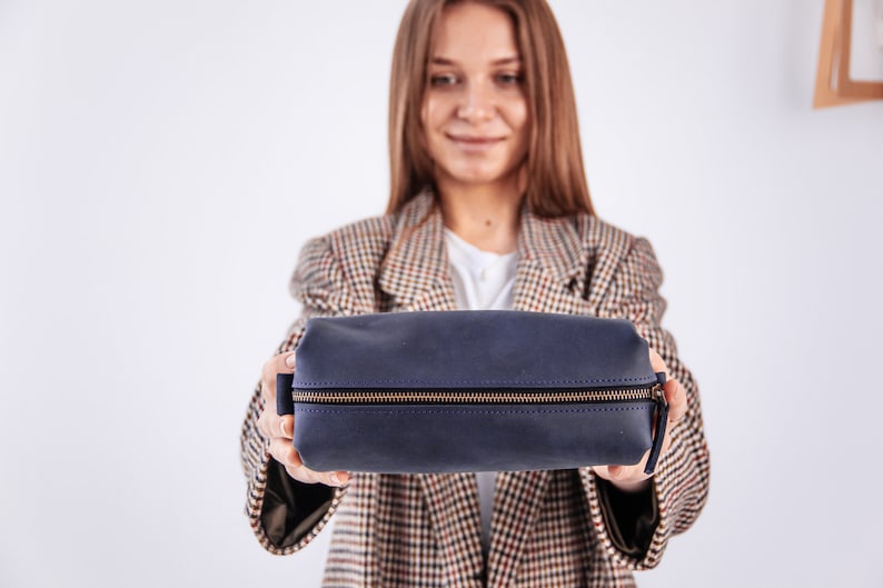 Peut inclure: Une trousse de toilette zipp&eacute;e bleu fonc&eacute; avec une fermeture &eacute;clair dor&eacute;e.