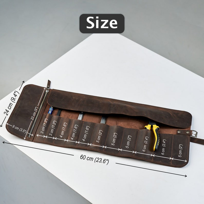 K&ouml;nnte beinhalten: Eine braune Leder-Werkzeugrolle mit 8 F&auml;chern zum Verstauen von Werkzeugen. Die Rolle ist 60 cm lang und 24 cm breit. Die Rolle ist ge&ouml;ffnet und zeigt die F&auml;cher und eine gelbe Zange im Inneren.