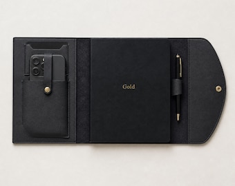 May include: A black folio organizer featuring a central notebook with the word Gold embossed in gold lettering. The left side includes a smartphone pocket with a snap closure, while the right side holds a black pen in a dedicated loop.