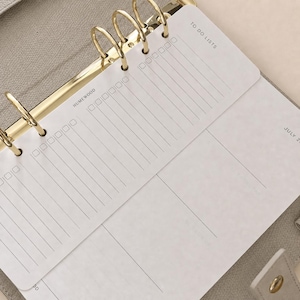 Peut inclure: Un agenda beige dot&eacute; d'un m&eacute;canisme de reliure &agrave; six anneaux dor&eacute;s contenant des feuilles blanches. Les pages pr&eacute;sentent du texte noir imprim&eacute;, notamment "TO DO LISTS" et "HUMEWOOD", ainsi que des colonnes verticales avec des cases &agrave; cocher.