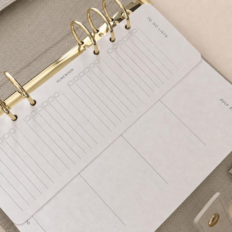 Peut inclure: Un agenda beige dot&eacute; d'un m&eacute;canisme de reliure &agrave; six anneaux dor&eacute;s contenant des feuilles blanches. Les pages pr&eacute;sentent du texte noir imprim&eacute;, notamment "TO DO LISTS" et "HUMEWOOD", ainsi que des colonnes verticales avec des cases &agrave; cocher.
