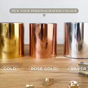 K&ouml;nnte beinhalten: Drei zylindrische Metallbeh&auml;lter in Gold, Ros&eacute;gold und Silber. &Uuml;ber den Beh&auml;ltern steht der Text "PICK YOUR PERSONALISATION COLOUR". Darunter stehen die W&ouml;rter "GOLD", "ROSE GOLD" und "SILVER".