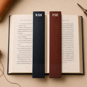 Könnte beinhalten: Offenes Buch mit zwei Leder-Lesezeichen. Ein Lesezeichen ist marineblau mit den Initialen "RSH" in Weiß, das andere ist braun mit den Initialen "FSE" in Gold. Das Buch ist auf den Seiten 24 und 25 geöffnet.