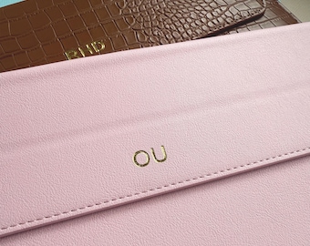 Könnte beinhalten: Nahaufnahme von zwei Leder-Clutch-Taschen. Die obere Tasche ist braun mit Krokodiltextur und goldenen Buchstaben mit der Aufschrift "PHD". Die untere Tasche ist rosa mit goldenen Buchstaben mit der Aufschrift "OU". Beide Taschen haben einen genähten Rand.