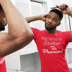 May include: A red t-shirt with the text "Don't Settle for Excellence Be Phenomenal" in white lettering.