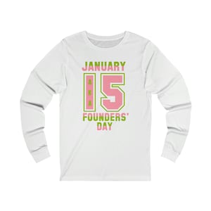 May include: White long-sleeve t-shirt with a pink and green graphic that says "JANUARY 15 AKA FOUNDERS' DAY".