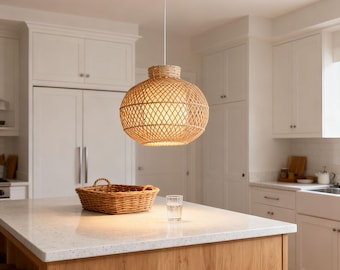 May include: A spherical rattan pendant light hangs in a kitchen. The light has a woven design and a white ceiling mount. A wicker basket and a glass of water are on the kitchen island, which has a wooden base.