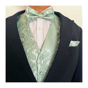 May include: A green paisley patterned vest with matching bow tie and pocket square. The vest has a button closure and the bow tie is tied.