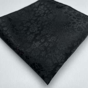May include: A black pocket square with a subtle floral pattern.