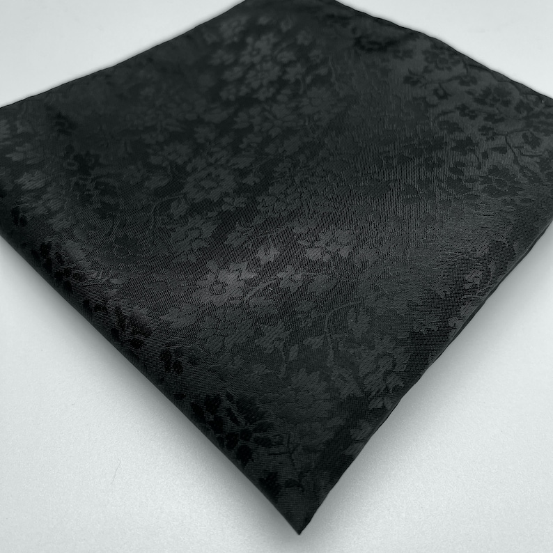 May include: A black pocket square with a subtle floral pattern.