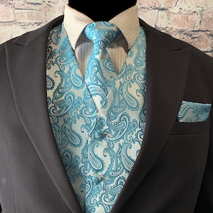 May include: A blue and white paisley patterned vest with a matching tie and pocket square. The vest is worn over a white dress shirt with a light blue striped pattern.