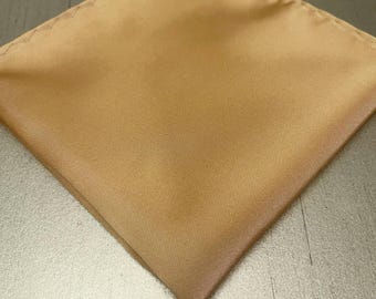 May include: A folded, square pocket square in a solid, light tan color. The fabric has a subtle sheen, and the edges are neatly finished. This accessory is suitable for formal or business attire.
