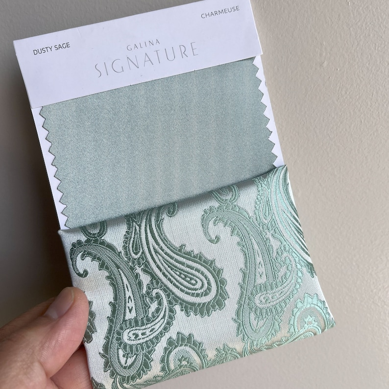 May include: A fabric swatch card with the text "Galina Signature" and the fabric names "Dusty Sage" and "Charmeuse". The card shows two fabric swatches, one in a solid dusty sage green color and the other in a paisley pattern with a white background and green paisley designs.