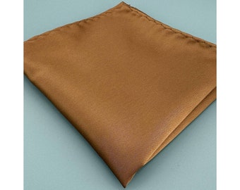 May include: A brown satin pocket square. The square is folded and ready to be placed in a suit jacket pocket.