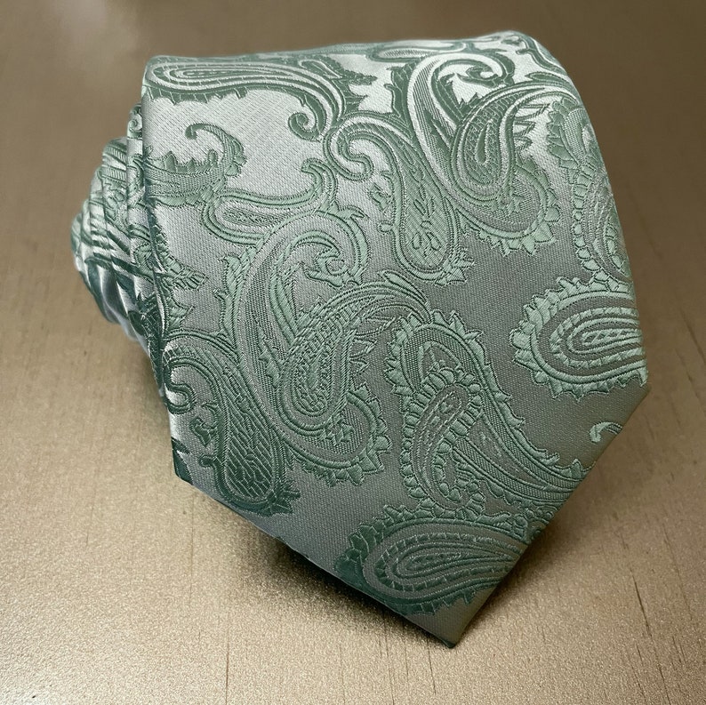 May include: A green paisley patterned tie. The tie is made of a silky material and has a classic design.