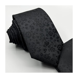 May include: A black tie with a subtle floral pattern. The tie is made of a smooth, silky fabric.