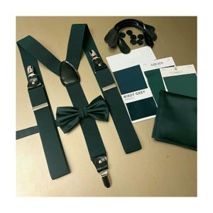 May include: Dark green suspenders with silver clips and a matching bow tie. The suspenders are made of a thick, durable fabric and have a classic design. The bow tie is made of a soft, silky fabric and has a subtle sheen.