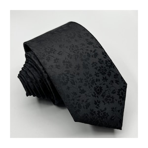 May include: A black tie with a subtle floral pattern. The tie is made of a smooth, silky fabric.