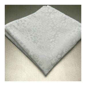 May include: A folded white pocket square with a subtle floral pattern. The fabric appears to be a soft, woven material. The square is neatly folded, showcasing the delicate design. Ideal for formal wear or adding a touch of elegance.