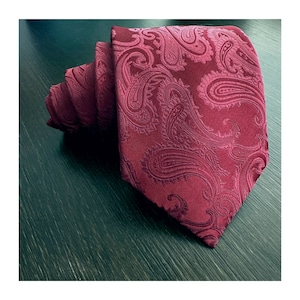 May include: A burgundy paisley patterned tie. The tie is made of a silky material and has a classic design.