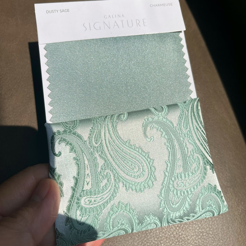 May include: Two fabric swatches, one a solid dusty sage green and the other a paisley pattern in the same color on a white background. The swatches are labeled "Dusty Sage" and "Charmeuse" with the text "Galina Signature" above.