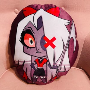 May include: Round plush pillow featuring a cartoon character with white hair, a red bow, and a red X over one eye. The character is wearing a red top and black skirt, holding a scythe. The pillow has a dark purple border.