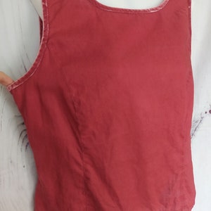 May include: A sleeveless red top with a velvet trim around the neckline.