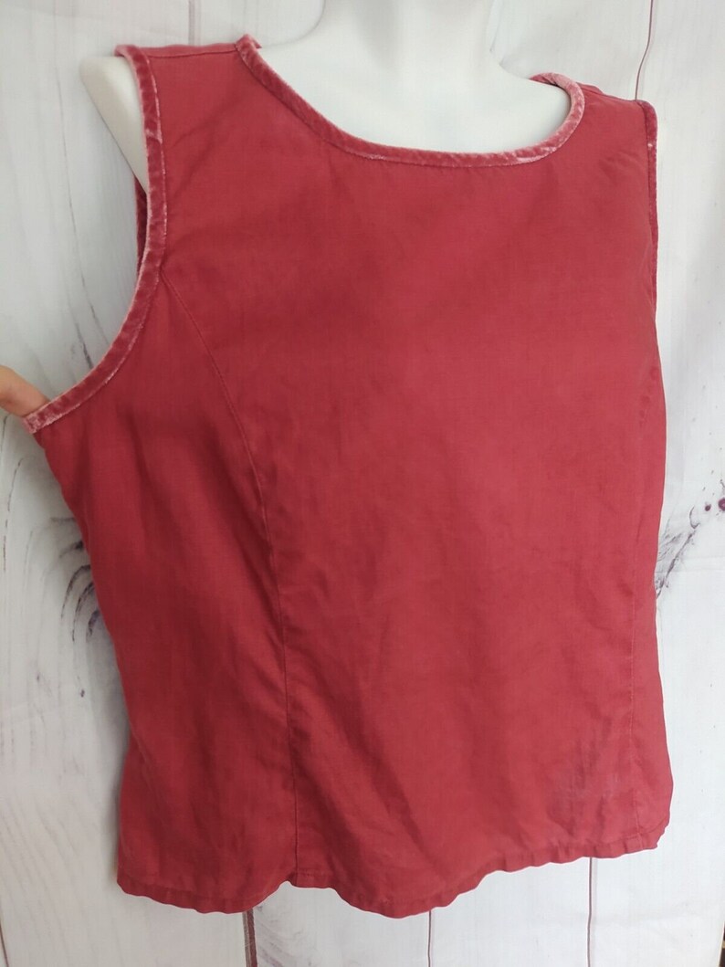 May include: A sleeveless red top with a velvet trim around the neckline.