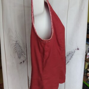 May include: A sleeveless red tank top with a velvet trim around the neckline. The top is made of a soft, lightweight fabric.