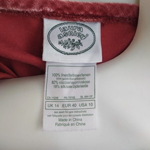 May include: A white tag with the Laura Ashley logo and size information. The tag reads "100% linen/lin/linnen/leinen trim/galon/band/besatz 82% viscose/rayon/viskose 18% silk/soie/zijde/seide CA 11249 RN 73785 BL 084 UF UK 14 EUR 40 USA 10 see seam for care instructions voir l'&eacute;tiquette pour les conseils d'entretien Made in China Fabriqu&eacute; en Chine"