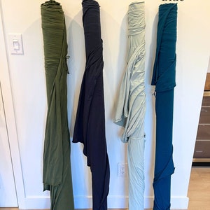 Puede incluir: Cuatro rollos de tela en diferentes colores: verde musgo, azul marino, espuma de mar y azul marroqu&iacute;. La tela est&aacute; enrollada y atada con una cuerda.