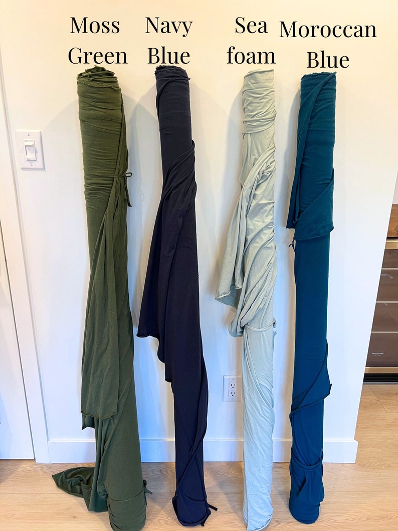 Puede incluir: Cuatro rollos de tela en diferentes colores: verde musgo, azul marino, espuma de mar y azul marroqu&iacute;. La tela est&aacute; enrollada y atada con una cuerda.