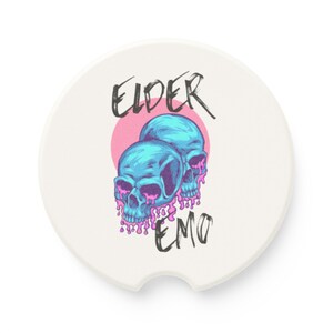 Puede incluir: Posavasos blanco para coche con un círculo rosa y dos calaveras azules con pintura rosa goteando. El texto "ELDER EMO" está escrito en negro.