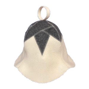 Puede incluir: Un sombrero de fieltro blanco y gris con un diseño en forma de estrella en la parte superior. El sombrero tiene un pequeño lazo en la parte superior y un ala ancha.