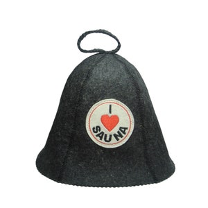 Puede incluir: Gorro de sauna gris oscuro con la parte superior redondeada y un peque&ntilde;o lazo. El gorro presenta un parche circular con un coraz&oacute;n rojo y las palabras "I LOVE SAUNA". Hecho de un material similar al fieltro, protege la cabeza en la sauna.