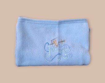 May include: A light blue fleece blanket with the word "Prince" embroidered in blue and white with a sword and shield design.
