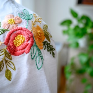 Mytoh Personalisiertes T-Shirt, handbestickt, 100 % Baumwolle. Modell mit aufgestickten Blumen am Hals.