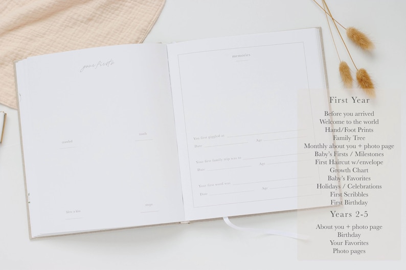 May include: An open baby memory book with white pages featuring printed lines and headings for recording milestones. The left page is titled "your firsts" and the right page includes a section for "our story" with prompts for dates and ages.