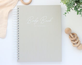 May include: A gray spiral bound baby book with the text "Baby Book - The first five years -" printed in white on the cover.